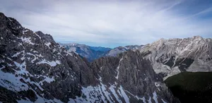 Jagged mountain peaks with scattered snow under cloudy sky. jigsaw puzzle