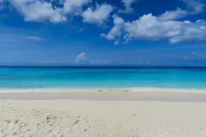 a sandy beach with blue water and clouds jigsaw puzzle