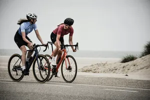 man and woman riding road bikes at the road near shore jigsaw puzzle