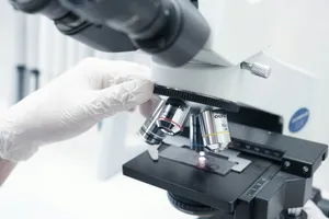 A person in white gloves looking through a microscope jigsaw puzzle
