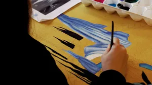 person holding black pen on blue textile jigsaw puzzle