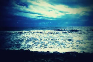 Captivating view of the ocean with dramatic waves and a moody sky, captured in rich blue tones. jigsaw puzzle