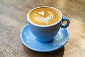 A beautifully crafted latte with heart-shaped art in a blue cup on a wooden table. jigsaw puzzle