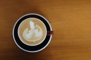 A beautifully crafted cappuccino with intricate latte art, viewed from above on a wooden table. jigsaw puzzle