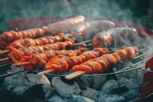 Delicious meat skewers and sausages grilling over a charcoal barbecue, emitting rich smoke and flavors. jigsaw puzzle