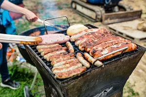 Grilling an assortment of sausages and bread at an outdoor barbecue on a sunny day. jigsaw puzzle