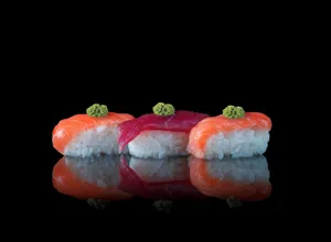 A close-up of nigiri sushi with salmon and tuna topped with wasabi on a reflective surface. jigsaw puzzle