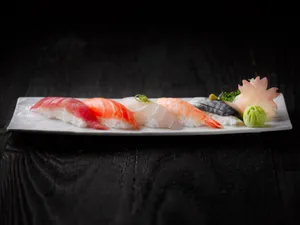 A beautifully arranged sushi platter featuring fresh sashimi on a sleek white plate with wasabi and garnish. jigsaw puzzle