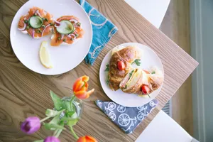 Top view of a wooden table with salmon bagels and croissant sandwich, adorned with tulips. jigsaw puzzle