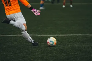 A soccer goalkeeper prepares to kick a colorful ball on a grass field. jigsaw puzzle