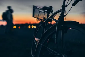 Silhouette of a bicycle at sunset with a blurry person in the background. jigsaw puzzle