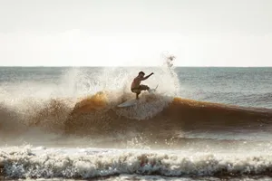 A dynamic action shot of a surfer catching a wave under a clear sky. jigsaw puzzle