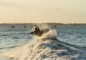 A surfer catching air during sunrise on ocean waves, showcasing skillful surfing and vibrant wave splash. jigsaw puzzle