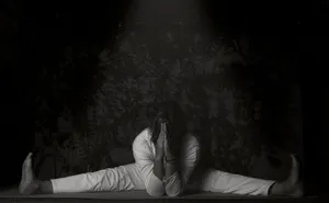 A woman practicing a yoga pose with a leg split indoors in monochrome lighting. jigsaw puzzle