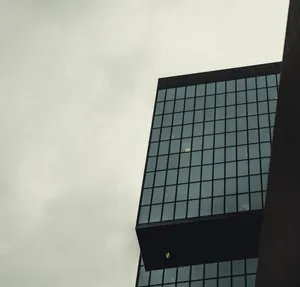 Low angle view of a modern skyscraper with a glass facade against a cloudy sky. jigsaw puzzle