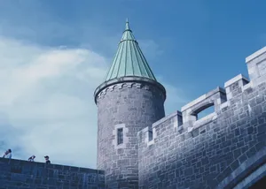 Low angle view of a historic castle tower and walls under a blue sky. jigsaw puzzle