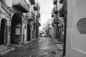 Black and white image of a quaint cobblestone street in Cefalù, Sicily, showcasing historic architecture. jigsaw puzzle
