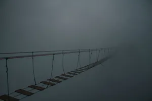 Spooky suspension bridge vanishing into a dense fog, creating a mysterious atmosphere. jigsaw puzzle
