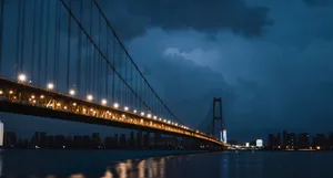 A stunning view of a suspension bridge lit up at night against a city skyline, creating a dramatic scene. jigsaw puzzle