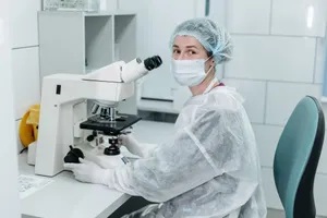 Scientist working with microscope in sterile lab environment, wearing protective gear and a mask. jigsaw puzzle