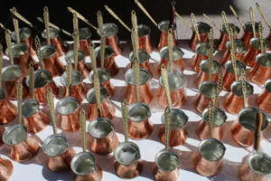 Top view of multiple copper coffee pots with brass handles arranged neatly on a white surface. jigsaw puzzle