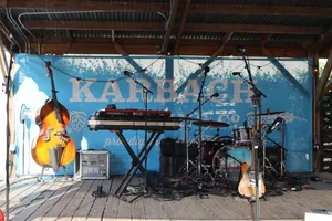 An outdoor stage with various musical instruments including a cello, drum set, and keyboard. jigsaw puzzle