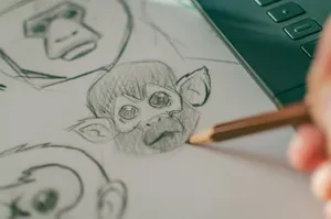 Close-up of hand sketching monkey faces on paper, showcasing artistic creativity. jigsaw puzzle