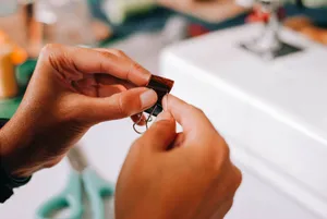Detailed close-up of hands making leather crafts with sewing machine in the background. jigsaw puzzle