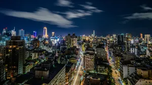 Vibrant cityscape at night with illuminated buildings and light trails. jigsaw puzzle