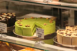 A green cake with walnuts in a display case. jigsaw puzzle