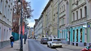A person walks down a street lined with buildings. jigsaw puzzle