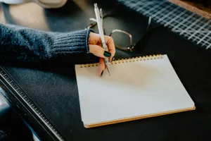 a person holding a pen and writing on a notebook jigsaw puzzle