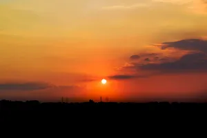 Stunning sunset view with vibrant orange and yellow hues over a silhouetted city skyline. jigsaw puzzle