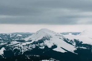 Breathtaking aerial view of a snow-covered mountain range under a moody winter sky, perfect for nature lovers. jigsaw puzzle