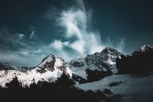 Breathtaking view of snow-covered mountains under a moody sky, showcasing nature's grandeur. jigsaw puzzle