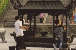 Two men light incense sticks at an outdoor shrine, symbolizing tradition and spirituality. jigsaw puzzle