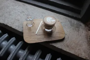 A cappuccino with latte art on a wooden tray by a window, creating a cozy atmosphere. jigsaw puzzle