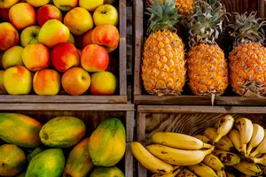 Colorful display of apples, pineapples, bananas, and papayas in wooden crates at a market. jigsaw puzzle