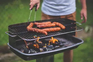 Man grilling sausages on an outdoor barbecue with flames and charcoal. jigsaw puzzle