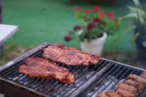 Juicy ribs sizzling on a charcoal grill in a garden setting. Perfect for summer BBQs. jigsaw puzzle