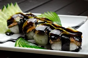 Close-up of sushi with eel, rice, and sauce, garnished with cucumber slices. Mouth-watering presentation. jigsaw puzzle
