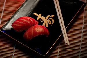 A close-up of two pieces of salmon sushi on a decorative plate with chopsticks. jigsaw puzzle