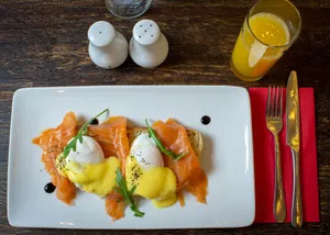 Indulge in a delicious plate of salmon eggs benedict with hollandaise sauce, served with orange juice. jigsaw puzzle