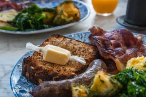 A hearty English breakfast featuring bacon, eggs, sausage, bread, and fresh greens. jigsaw puzzle