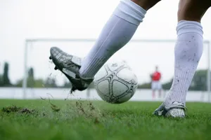 Close-up of a soccer player kicking a ball with motion and intensity on a grass field, showcasing action and sport. jigsaw puzzle