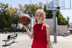 Red-haired girl standing confidently with basketball on an outdoor court, ready to play. jigsaw puzzle