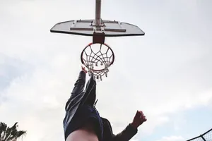 Low angle shot of a person dunking on an outdoor basketball hoop during the day. jigsaw puzzle