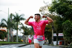 Smiling athlete in pink shirt flexing muscles while running a race outdoors. jigsaw puzzle