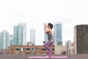A woman practices yoga on a rooftop with an urban cityscape backdrop, embracing health and fitness. jigsaw puzzle