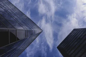 Stunning low angle shot of towering glass skyscrapers against a vibrant blue sky with fluffy clouds. jigsaw puzzle